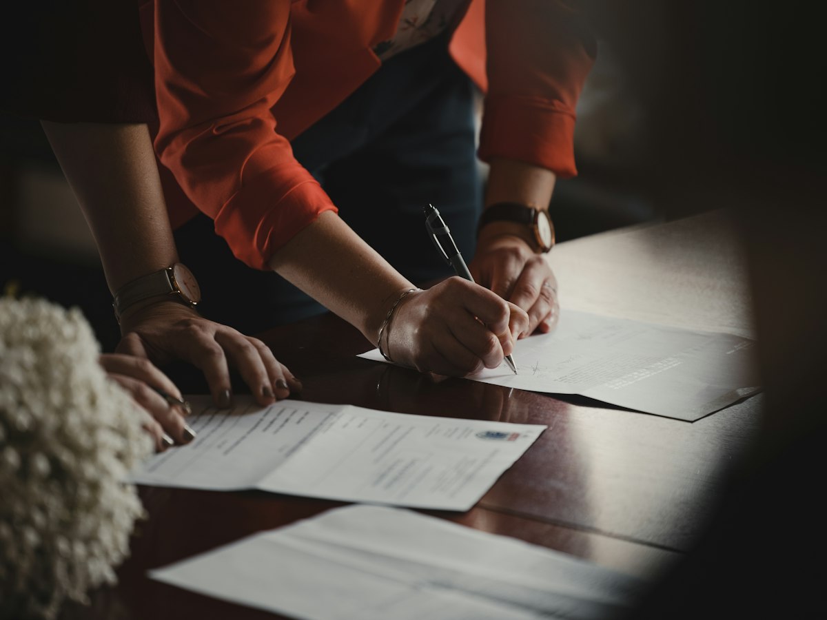Close-up of a hand signing paperwork with a pen