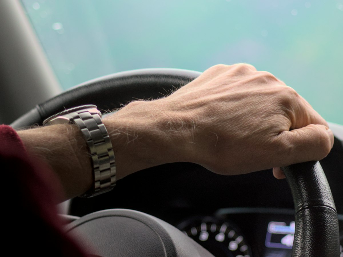 Close-up of hands on a car steering wheel while driving