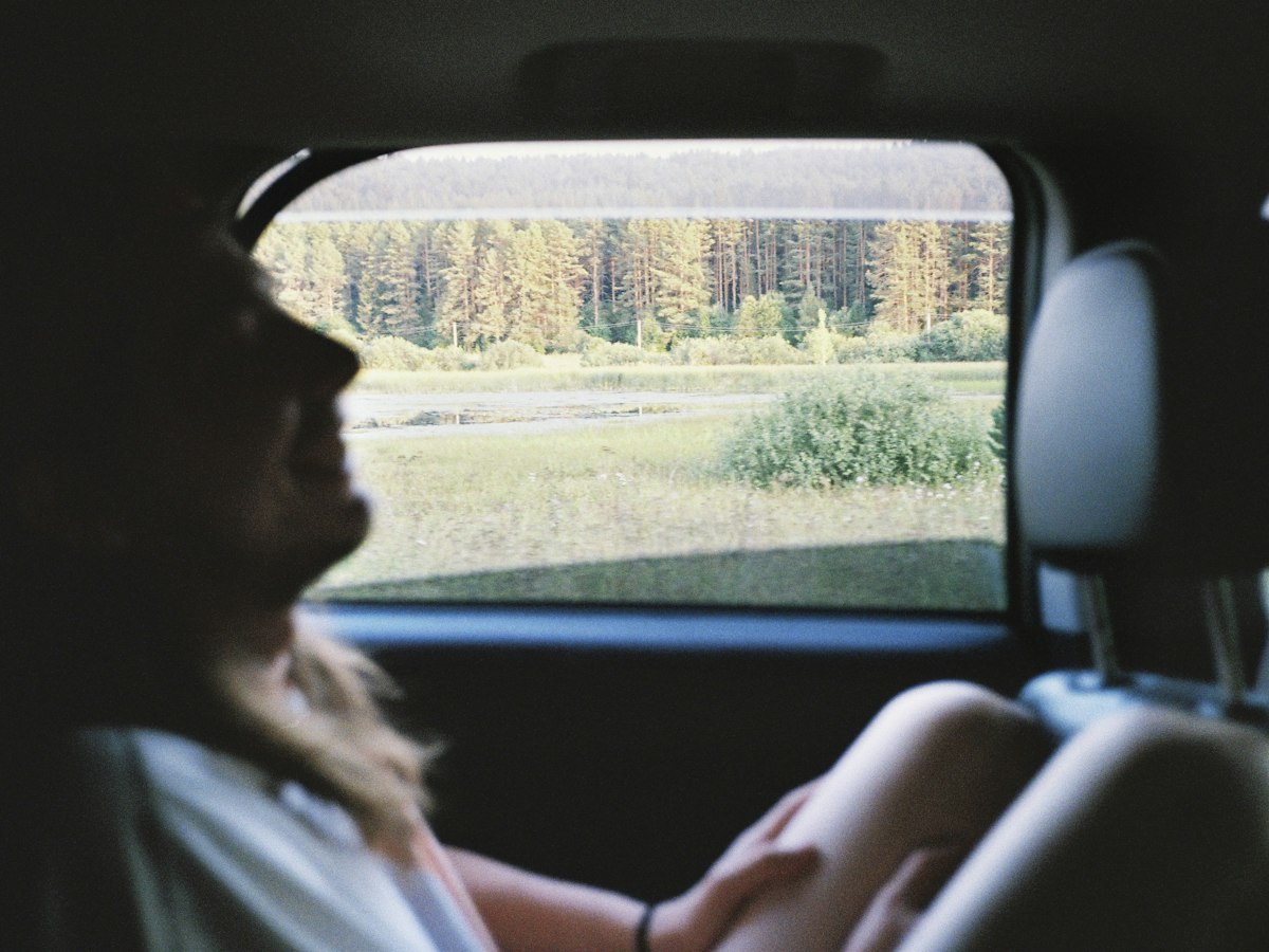 A passenger looking out the back seat window during a drive