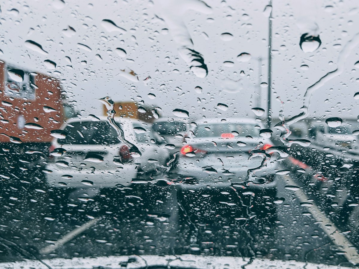 Rain drops on a car windshield with traffic blurred in the background